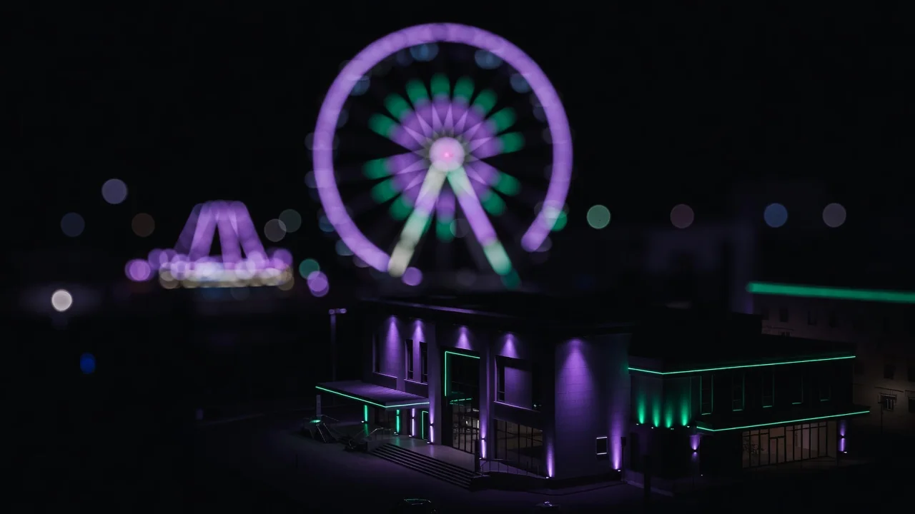 Ferris wheel lights blurred into bokeh circles at night in purple and green